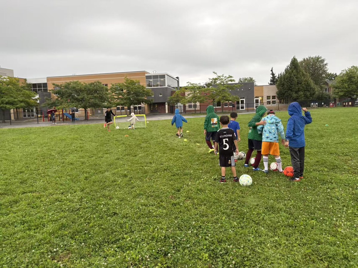 Children practicing soccer during rainy fall training